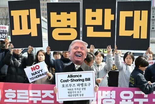 A South Korean protester wears a mask of US President Donald Trump during a protest against his request to dispatch warships to the Strait of Hormuz