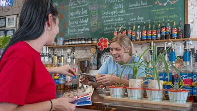 Ashlie Leiweke receives cash from Jonna Gibson, left, at Just be Kind Cafe in De Soto.