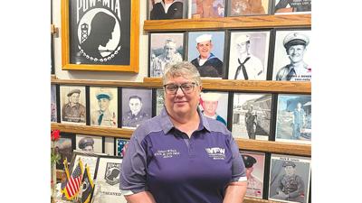 Veteran Quincy Myrick stands in front of photos of her and her husband, Bill, on the De Soto VFW post’s member wall.