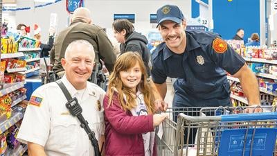 Fire Chief Mark Earls, left, and Firefighter Joe Berra, both of Jefferson R-7 Fire Protection District, shop with Elaina, 9, of Crystal City during the Jeffco Shop with a Cop event on Dec. 8.