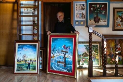Painter Pavel Hajko poses with his work at his home studio northern Serbia