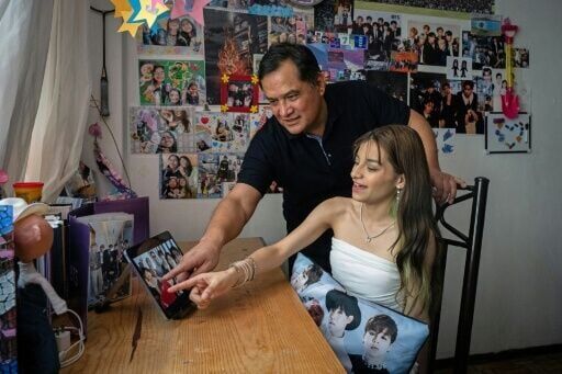 Ana Campos Rodríguez, una fan mexicana del grupo surcoreano de K-pop BTS, y su padre Lucio Campos Godínez señalan la imagen de los integrantes del grupo en una tableta en su casa de Ciudad de México el 29 de abril de 2026.