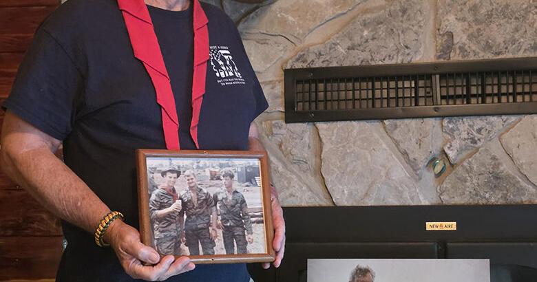 Kenny McLacklan holds a photo of Harris and himself when they were in Vietnam.