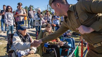 A U.S. 2nd Rangers Infantry Battalion of St. Louis reenactor shakes the hand of John “Bill” Burkholder, 99, who served in World War II on the USS Pennsylvania in the Navy.