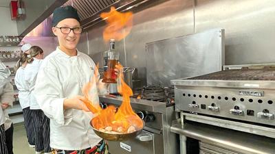 Chloe Ziegler, a junior at Northwest High School, shows off her flambeing skills while other students work on several different recipes.