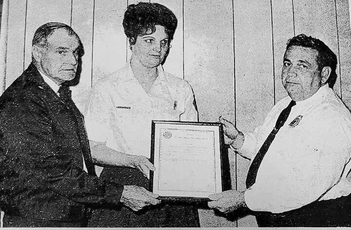 Harriett Vaucher, center, accepted the Certificate of Merit from Robert Watts of the St. Louis County Fire Chiefs Association on behalf of her late husband George H. Manetzke Jr.