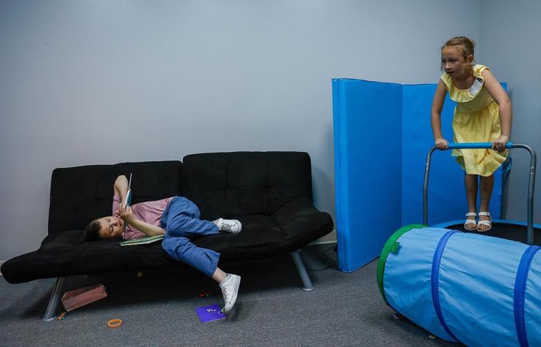 Carter, left, 11, flips through a book while his sister Julia, 7, jumps