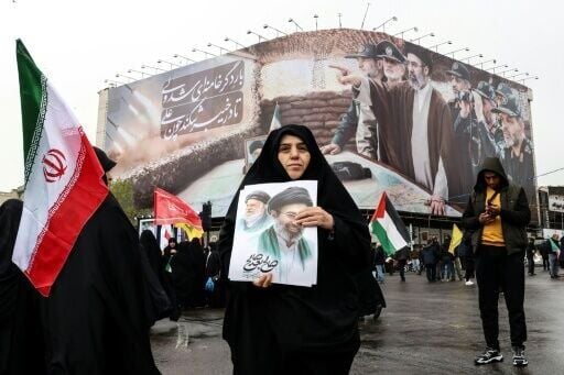 A woman holds a picture of Iran's new supreme leader Ayatollah Mojtaba Khamenei as she takes part in a rally in Tehran on March 13, 2026