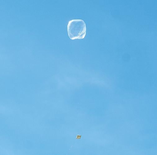 The balloon, tethered to a transmitter, rises into the sky.