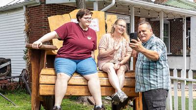 Bob Mira films Bethany and Lisa sitting in the largest chair in Jefferson County outside Kindred Crows Olde Country Store in Kimmswick.