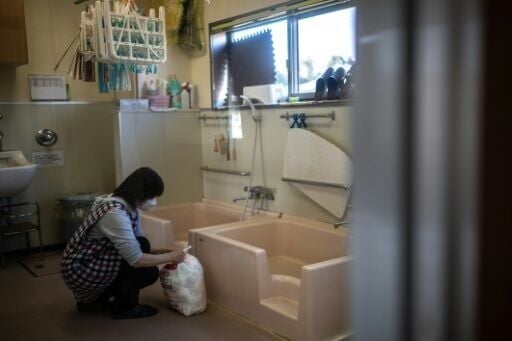 A staffer collects a bag of used diapers at a nursery school in Osaki town, Kagoshima Prefecture