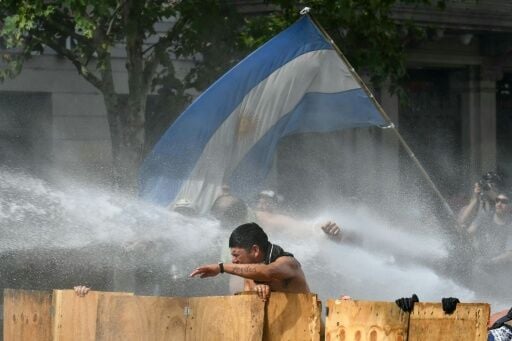 Argentine demonstrators are hit by water cannon fired by riot police during a protest in Buenos Aires against proposed labor reforms