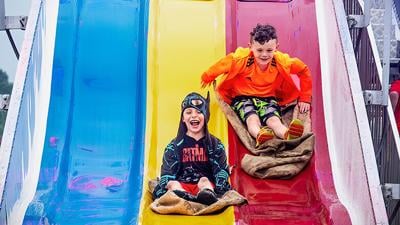 Wyatt Mcglaughlin and Austin Voyles of Hillsboro race down the slide at the 2023 Hillsboro Homecoming Festival.