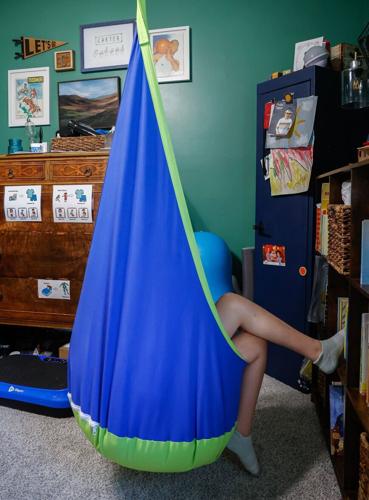 Carter, 11, watches videos on his iPad while sitting in an indoor swing
