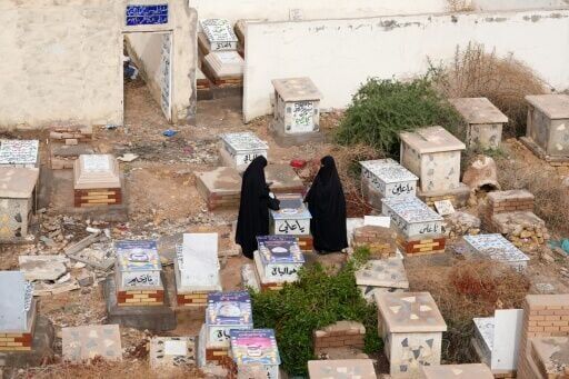 Iraqi Shia women visit a grave at Wadi al-Salam Cemetery in Iraq's holy city of Najaf as the war rages