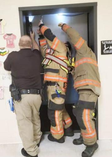Antonia firefighters work to lower an elevator that got stuck twice in one day last week, first trapping five students and later a custodian.