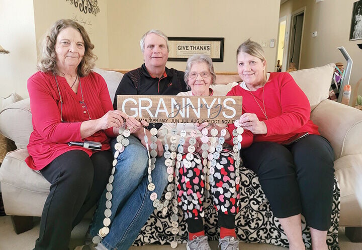 Elenora Biermann, center right, and her children, from left, Ellie McCarthy, Bill Biermann and Helen Greaves, hold up an expandable sign that lists nearly every name and birthday of Elenora’s grandchildren and great-grandchildren.