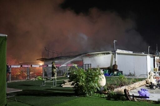 Firefighters work to stop a fire caused by debris after a rocket interception in a residential area near Tel Aviv