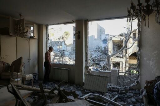 An Iranian resident looks out the window of his damaged home after Israeli-US strikes in Tehran on April 7, 2026