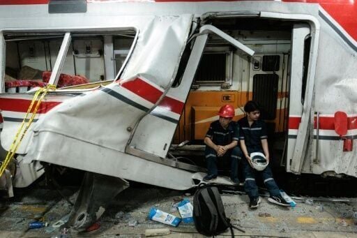 Workers sit at the site of a train collision after a passenger train locomotive pierced through the rear car of a commuter train at Bekasi Timur station in Bekasi, West Java on April 28, 2026