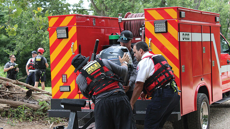 Firefighters Jacob Boedy and Matt Miniea with the High Ridge Fire Protection District, along with Eureka Fire Protection District Chief Scott Barthelmass, put an inflatable boat motor on a trailer.