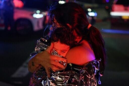 A woman holds her baby in a blanket after a shooting incident at Bondi Beach in Sydney on December 14, 2025.