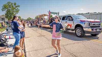 Alanna Oliver, the daughter of Drummond Florist’s owner, Julia Ott, hands out carnations along the parade route.