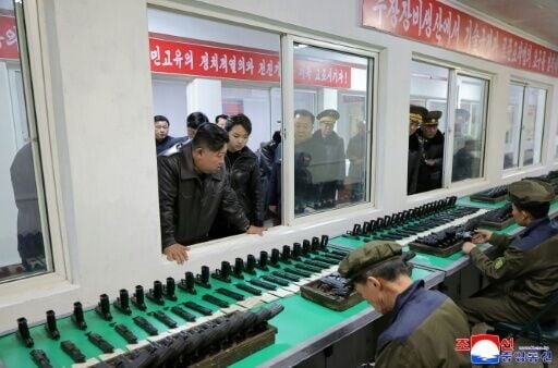 North Korean leader Kim Jong Un (C) and his daughter Kim Ju Ae (center R) inspect the production of a new type of handgun at a munitions factory at an undisclosed location in North Korea