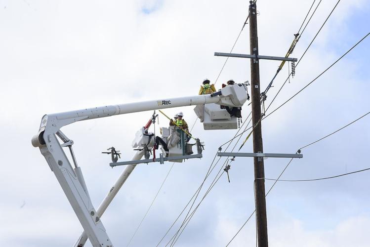 Construction workers fix the power lines on Tuesday, in Slater