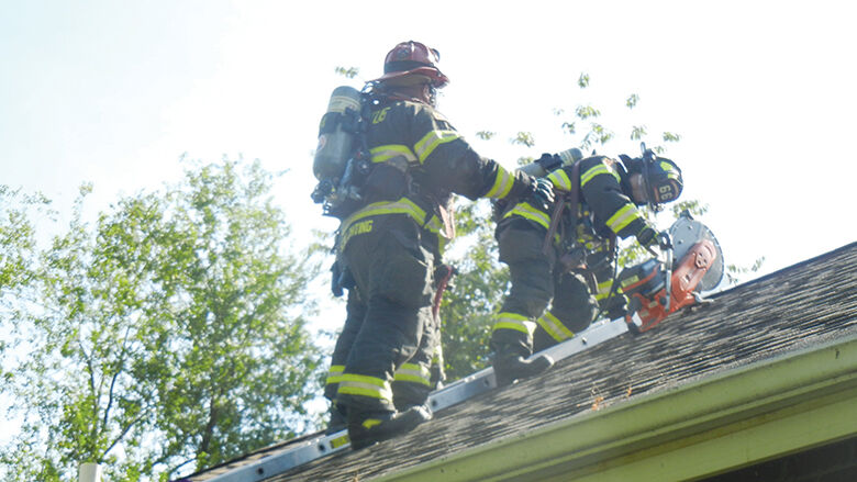 Festus firefighters use a power saw to cut through the roof while training.