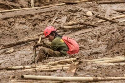 A rescuer rests as they search for victims buried by a landslide in Pasirlangu village