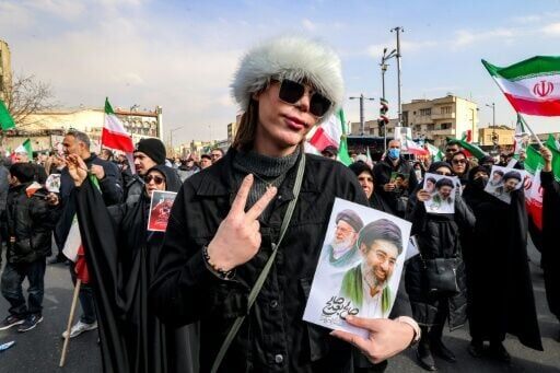 A woman holds a picture of Ayatollah Mojtaba Khamenei (R) and his late father Ali Khamenei