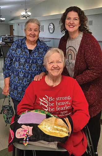 Sharon Miller, left, and Emily Bowman Cook present one of their custom fidget mats to Crystal Oaks resident Rose Rueve.
