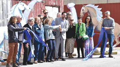 Marita Wassman and board president Dominic Lampasi cut the ribbon, held by BriAnn Session and Rick Wassman.