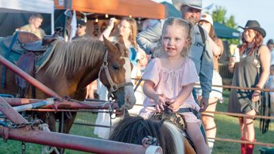 Willow Westcott, 2, rides a pony on June 13 at the Jefferson County Rodeo in Hillsboro. Kids lined up to take rides on horses outside the main arena.