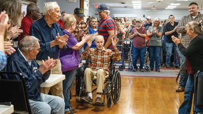 Larson Wile, 106, raises his hands while the crowd gives him a round of applause for his service.