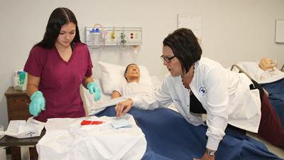 Jefferson College CNA program instructor Ginger Hand, right, works with a Health Services ATS student.