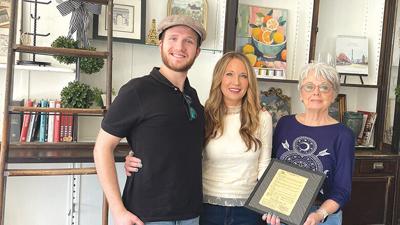 Barb Boyer, pictured with Gina and Grant Otto, holds up a framed copy of her Frenchy’s Carryout menu from the mid-1980s.