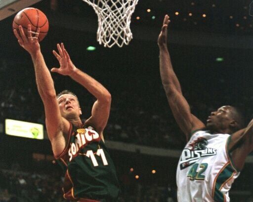 Seattle SuperSonics' Detlef Schrempf (L) drives past Detroit Pistons' Theo Ratliff (R).