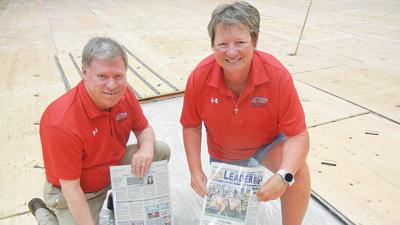 Roger Barrentine, Jefferson College director of public information and marketing, and Marie Self, the college’s athletic site supervisor, put laminated pages of the June 16, 2022, Leader under the new flooring for the Fieldhouse gym.