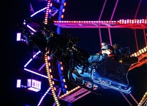 A performer dressed as Santa Claus greets visitors as he rides his sleigh with reindeers over a Christmas market in Berlin