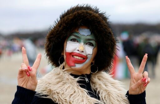 A woman made up in the colors of Iran flashes the victory sign as she arrives for the demonstration