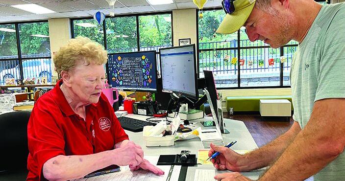Marilyn Parr issues the final library card of her 44-year career to Crystal City Mayor Mike Osher.