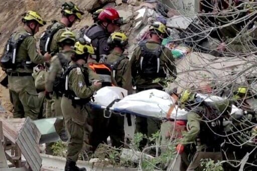 Israeli rescue teams pull a body from the rubble of a residential building in Haifa after an Iranian missile hit