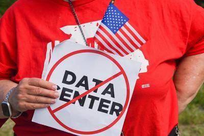 A protester holds a sign opposing the construction of a data center