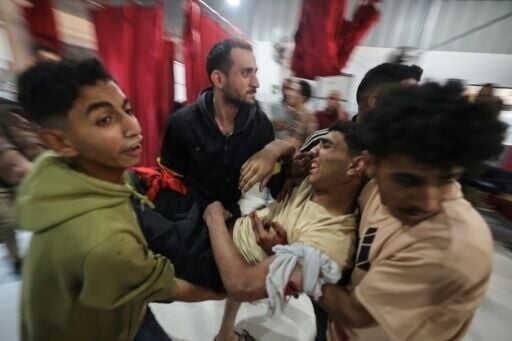 Palestinians carry an injured man at Al-Awda Hospital