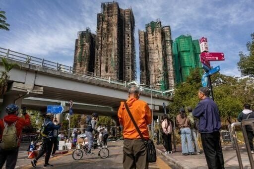 People look at the aftermath of a major fire that swept through several apartment blocks at the Wang Fuk Court residential estate