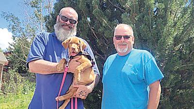 Local veteran Scott holds his new service dog, Ruby, given to him by Dogs That Help, a volunteer organization that provides fully trained service dogs for free. The group’s CEO, Luke Reinhold, is at right.