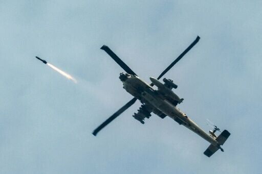 An Israeli air force AH-64 Apache attack helicopter fires rockets while flying along the border with Lebanon