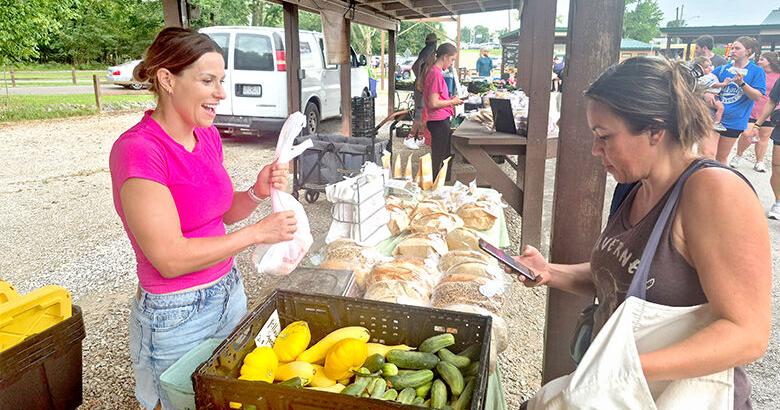 Apryl Ott of Julie’s Produce, left, completes a sale Aug. 19 with Aleisha Althage of Arnold during the Farm Fresh at Sunset market. It was the first evening weekday market held at the Arnold Farmers Market.